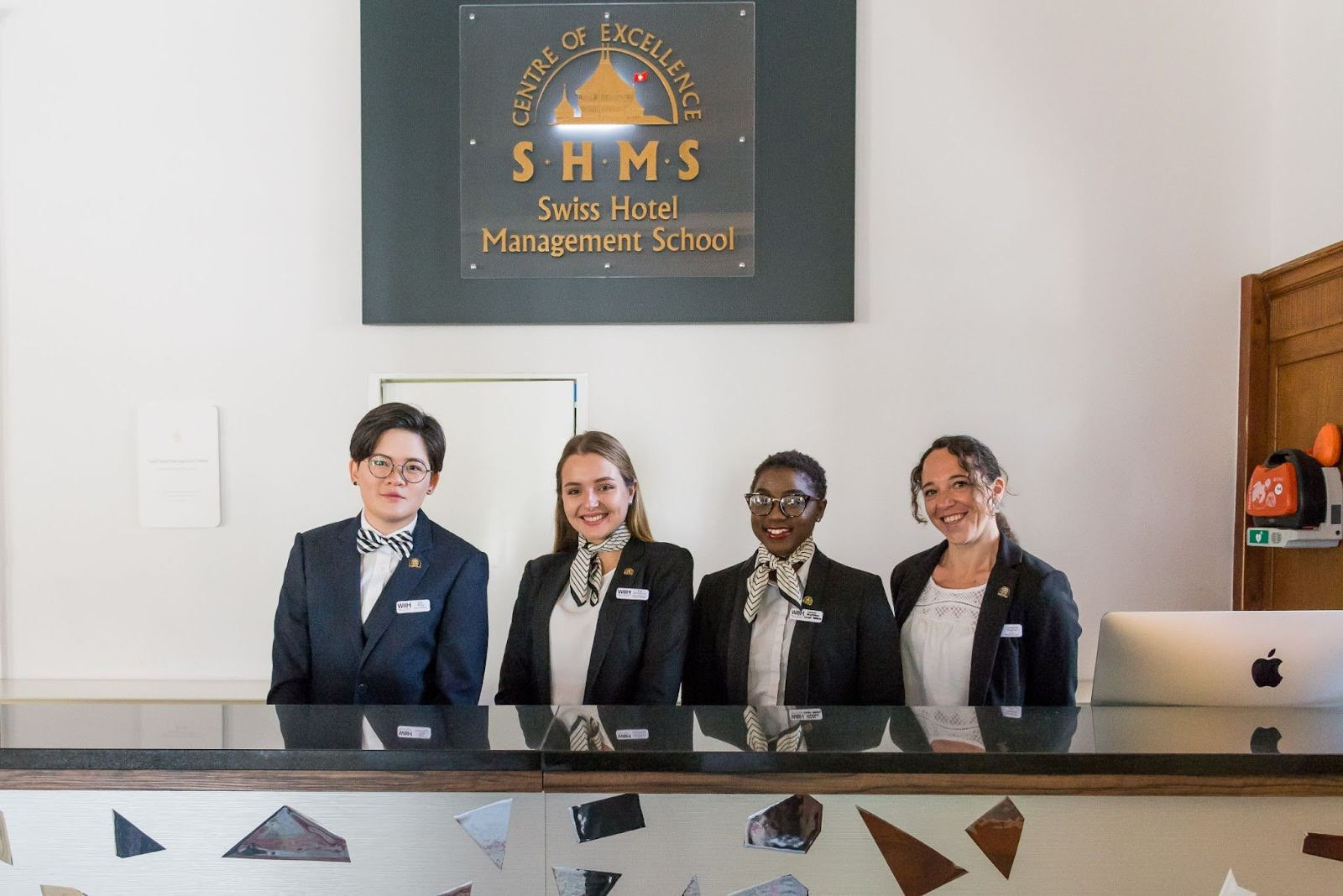 Four hotel receptionists smiling at the camera