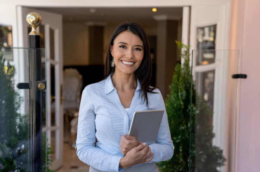A woman with a laptop on her hands smiling at the camera.
